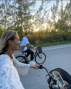 two people riding bikes down the street with one person pushing a stroller behind them