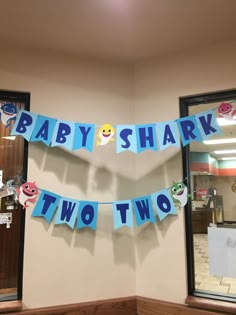 a baby shower banner hanging on the wall in front of two windows with stickers attached to it