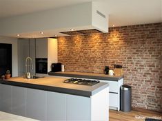 a modern kitchen with brick wall and white cabinets