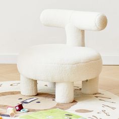 a large white chair sitting on top of a wooden floor next to a pile of toys