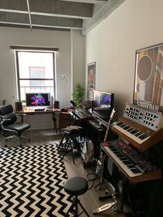 a living room filled with furniture and musical equipment in front of a large window on top of a black and white checkered rug