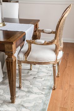 a dining room table with two chairs and a rug