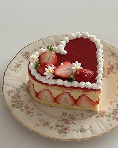 a heart - shaped cake with strawberries on top is sitting on a floral plate