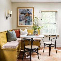 a table with two chairs and an umbrella in a room next to a window,