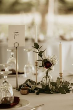 the table is set with candles, flowers and place cards for guests to sit at