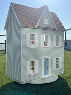 a model house sitting on top of a lush green field in front of a blue sky