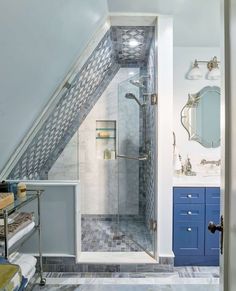 an attic bathroom with blue cabinets and marble tile flooring on the walls, along with a walk in shower