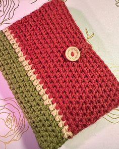 a red and green crocheted bag with a button on it's side