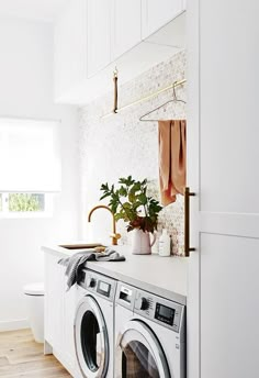 a washer and dryer in a room with white walls, wood floors and wooden flooring