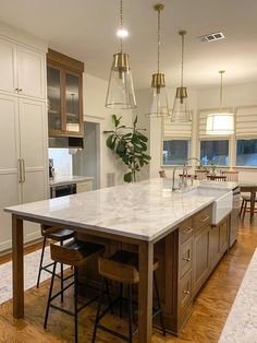 a large kitchen island with two stools in the middle and an island table on one side