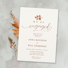 a wedding card with the words we're engaged written on it next to some flowers