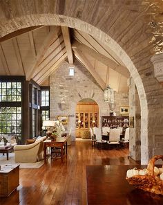 a living room filled with furniture and a stone archway leading to an open floor plan