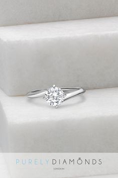 a diamond ring sitting on top of a white stone stepbox with the words purely diamonds written below it