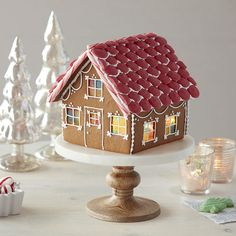 a gingerbread house is sitting on a cake plate