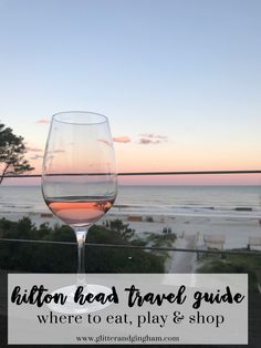 a glass of wine sitting on top of a balcony next to the ocean with text overlay reading hilton head travel guide where to eat, play & shop