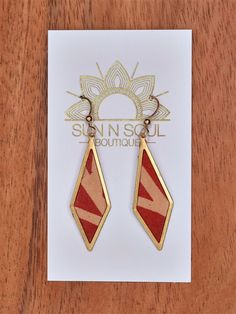 a pair of red and gold earrings sitting on top of a card