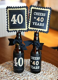 two beer bottles are decorated with black ribbon and bow for 40 years anniversary party favors