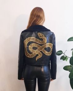 Beautiful vintage moto jacket in black faux leather, custom hand painted with unique mystic serpent artwork in gold paint. Silver tone zip and faux leather belt. Black faux fur collar - not detachable. Made in Italy Size XS/S Free Shipping Each item is carefully and nicely wrapped in tissue paper and shipped in a bubble bag or box. Find more of my vintage pieces at www.chezmargot.etsy.com Paint Leather Jacket, Serpent Artwork, Snake Jacket, Hand Painted Jacket, Black Shearling Jacket, Painted Leather Bag, Painted Leather Jacket