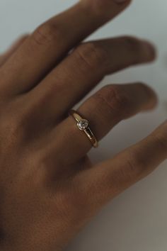 a person's hand with a gold ring on top of their finger and a diamond in the middle