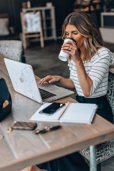 a woman drinking coffee while using her laptop