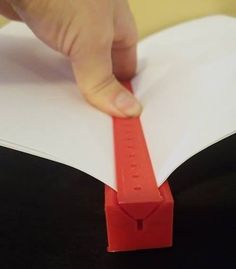 a person is cutting out a piece of paper with a red tape on top of it