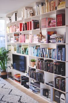 a bookshelf filled with lots of books in a living room next to a window