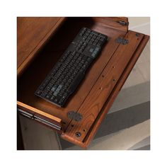 a computer keyboard sitting on top of a wooden desk next to a stair case in a room