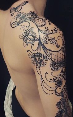 the back of a woman's shoulder with an intricate tattoo design on her arm