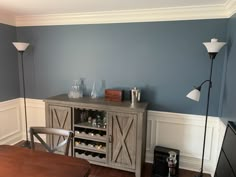 a dining room with blue walls and white trim on the walls, a wine cabinet in the center