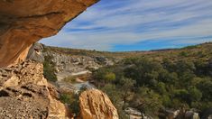 a rocky cliff overlooks a river in the distance