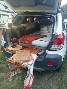 the back end of a van with two beds in it and an open trunk door