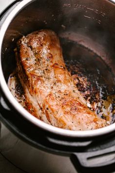 two pieces of meat are cooking in a pot on the stove top with some seasoning