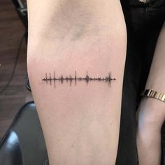 a person with a tattoo on their arm that has an equal sound wave in it