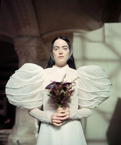 a woman in a white dress holding a bouquet of flowers