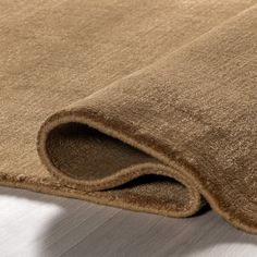 a close up view of a brown rug on the floor with white sheets in the background