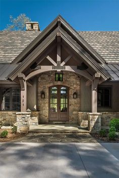 the front entrance to a house with stone and wood trimmings on the roof