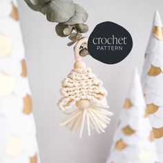 a crochet bell ornament hanging from a tree with gold and white ornaments