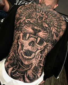 a man with a tattoo on his back has a tiger and skull design on it