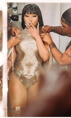 a woman in a gold bodysuit getting her makeup done