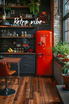 an old fashioned red refrigerator sitting in a kitchen next to a wooden table and chairs