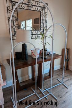 a mirror sitting on top of a wooden table next to a plant in a vase