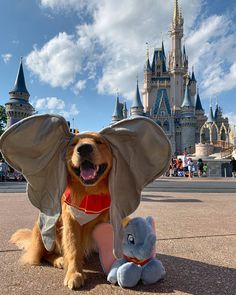 a dog wearing an elephant costume sitting next to a stuffed animal in front of a castle