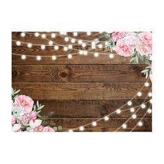 pink flowers and lights are hanging on a wooden wall with string lights in the background