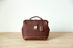 a brown leather handbag sitting on top of a wooden table next to a white wall