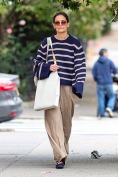 a woman walking down the street carrying a white bag