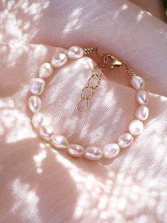 This shimmering porcelain white freshwater pearl bracelet is a must have staple. Wear this gold pearl bracelet to remind yourself of the soothing sands of Hawaii.✦ DETAILS ✦✧ Name: Ala (AH lah) - fragrant; esteemed.✧ Adjustable Length from 6.5"-8".✧ White 6-7mm Freshwater Pearls.✧ 18kt Gold Filled with lobster clasp.✧ All Ke Aloha Jewelry pieces come packaged thoughtfully, beautifully, and ready for gift giving. Luxury Minimalist Chain Bracelet With Oyster Design, Luxury Dainty White Pearl Bracelet, White Charm Bracelet For Beach, Feminine Pearl Drop Bracelets, Feminine White Pearl Bracelet As A Gift, Feminine White Pearl Bracelet Gift, Elegant Everyday Cream Jewelry, Single Strand Baroque Pearl Bracelet As Gift, Feminine White Pearl Bracelets