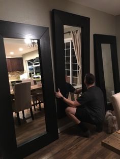 a man sitting on the floor in front of a mirror looking at himself through it