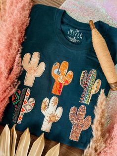 a t - shirt with cactus designs on it next to some feathers and other items