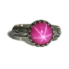 "10mm Lab Created Pink Star Ruby Ring. Fascinating Brilliance! This stone is reminiscent of the vintage “Lindy” synthetic Star Ruby of the 50s thru 70s. The star effect, known as an “asterism”, is more defined in a lab-grown Ruby. They are identical in chemical composition, brilliance, and physical appearance as their natural counterpart, however they have fewer flaws, are not mined from the ground, and are much less expensive. They are an extremely durable stone with a Mohs scale hardness or 9 Star Effect, Blue Star Sapphire Ring, Aventurine Ring, Star Ruby Ring, Star Sapphire Ring, Blue Star Sapphire, Physical Appearance, Crown Vintage, Flower Band