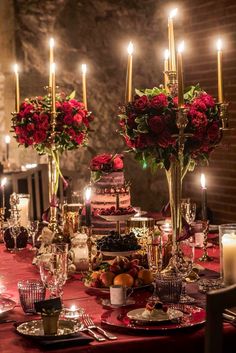 a dining table with candles and flowers in vases on the top is set for a formal dinner